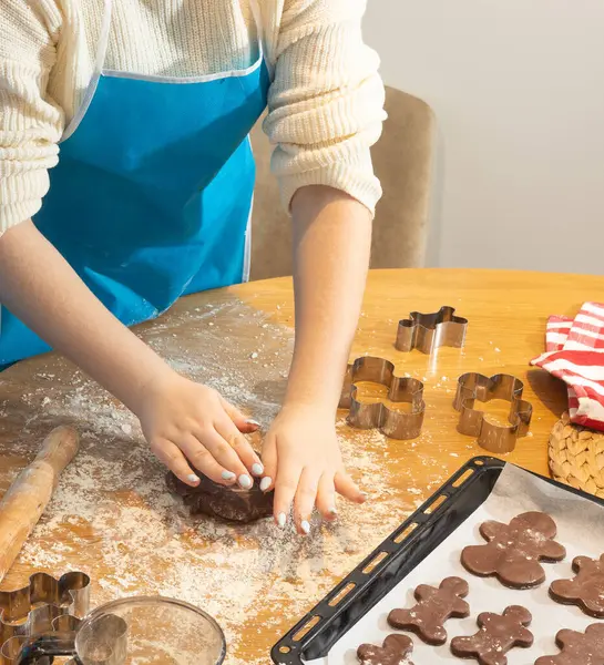 Çocuk ellerine yakın çekim. Mutfak masasında un ve keskiyle kurabiye hamuru hazırlıyorlar. Aile yemekleri, kaynaşma ve yaratıcılık kavramı parlak doğal ışıkta