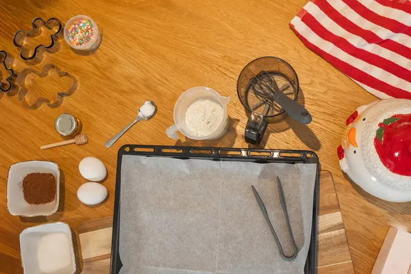 Kurabiye pişirme malzemeleri ve aletlerinin genel görünümü: un, yumurta, şeker, kakao, kurabiye keskisi ve bayram dekorasyonu. Sıcak ve renkli bir Noel mutfağı.