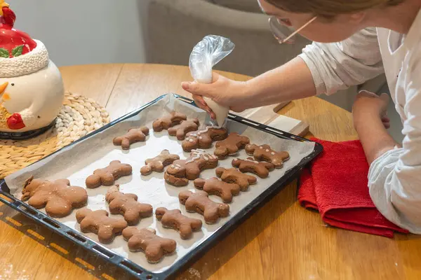 Çocuklar, ebeveynler ve çocuklar evde kurabiye pişiriyorlar. Un kaplı masada kurabiye keskisi kullanarak çikolata hamuru yuvarlamak. Ev yapımı pastalar ve tatil aile aktiviteleri.