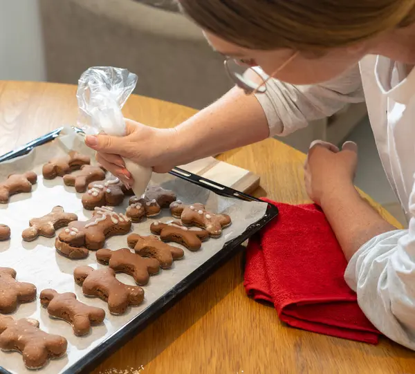 Çocuklar, ebeveynler ve çocuklar evde kurabiye pişiriyorlar. Un kaplı masada kurabiye keskisi kullanarak çikolata hamuru yuvarlamak. Ev yapımı pastalar ve tatil aile aktiviteleri.