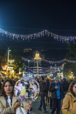 HAIFA, ISRAEL 23 ARALIK 2024: İnsanlar arka planda Bah Gardens 'ın aydınlatıldığı festival ışıkları altında kış tatillerini kutluyor