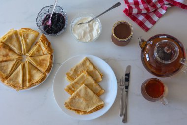 Reçelli gözleme, ekşi krema ve beyaz arka planda çay. Geleneksel kahvaltı ya da tatlı ev ortamında servis edilir. Üst görünüm, düz görünüm