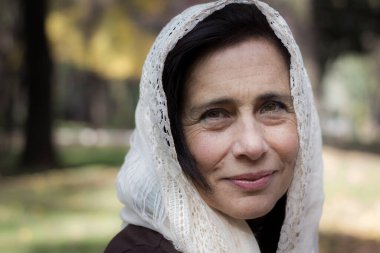 Beyaz şallı orta yaşlı güzel bir kadının portresi ve açık havada düşünceli bir ifade. Başında beyaz peçesi olan genç bir kadın. Arap, Müslüman görünümü