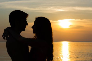 Lovely Valentine's Day scene of a young couple silhouettes hugging each other by the sea at fabulous sunset in the island of Koh Phangan, Thailand. Summer vacation, romantic travel destination concept