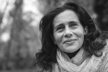 Uzun saçlı ve boynunda şal olan gülümseyen olgun bir bayan. Siyah beyaz portre. Mutlu orta yaşlı kadın. Emeklilik, sağlık sigortası kavramı