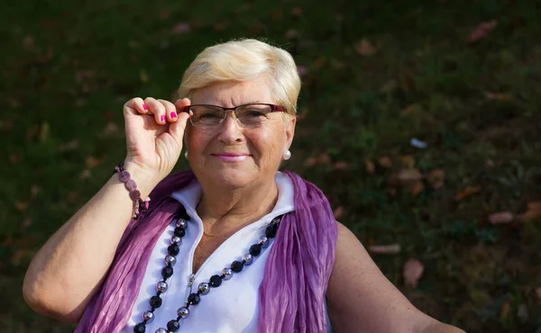 Smiling Senior Woman Sitting Park Bench Holding Eyeglasses Older Blonde — Stockfoto