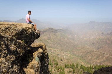 Pico de las Nieves, Gran Canaria 'da dağ yamacında oturan yalnız bir adam. Korkusuz dağcı İspanya 'nın Kanarya Adaları' nda güneşli bir günde harika manzaranın tadını çıkarıyor. Cesaret, cesaret, cesaret kavramları