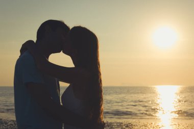 Sevgililer Günü 'nde, Tayland' ın Koh Phangan adasında deniz kenarında gün batımında birbirini kucaklayan genç bir çiftin güzel bir sahnesi. Yaz tatili, romantik seyahat konsepti.