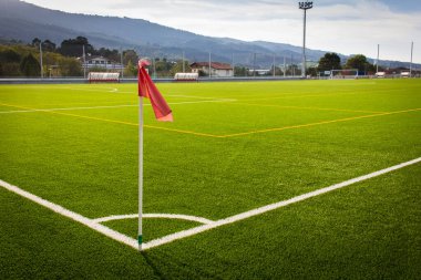 Red flag on corner kick in green artificial grass soccer field. Football World Cup concept clipart