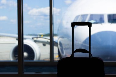 Bagaj çantası pencerenin yanında, uçaklar havaalanında.  