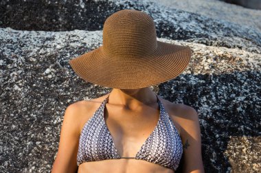 Rock 'ın yanında şapka ve bikinili sütyen giyen model kadın.