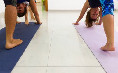 Erkek ve kadın yoga sınıfında esniyorlar, çıplak ayaklı insanlar minderlerde. 