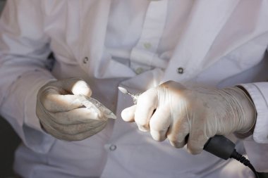 Lastik eldivenli dişçi elleri plastik diş modelini parlatıyor. 