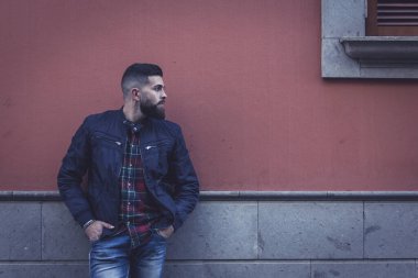 Genç hippi sokakta dikilip yan tarafa bakıyor. Mavi kotlu, ceketli ve duvara dayanmış damalı erkek manken. Karanlık etki