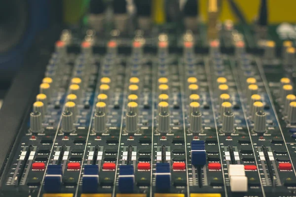 Close up on professional audio mixer. Mixing desk, sound board. Blue, yellow and red controls and equalizers. Film and music studio recording equipment