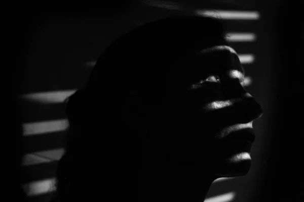 顔にストライプの影を持つ暗闇の中で若い女性の黒と白の肖像画 低キーファッションモデルセッションコンセプト — ストック写真
