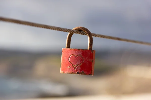 鋼線に取り付けられた赤い愛南京錠 手すりの屋外にぶら下がって刻まれた心の形を持つ錆びたロック バレンタインデー 記憶の概念 — ストック写真