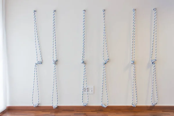Yoga ropes hanging on studio wall. White background. Iyengar yoga props