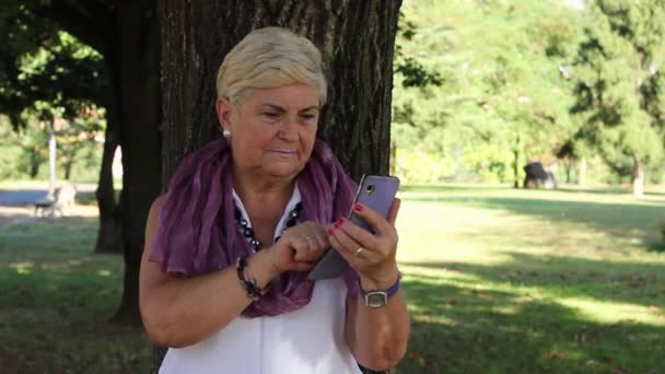 Donna Anziana Sorridente Con Smart Phone Appoggia Sull Albero Del — Video Stock