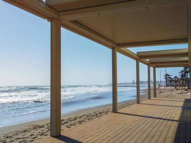 Pergola on the beach with a sea of big waves