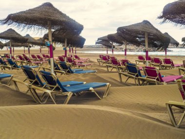 Plaj sandalyeleri ve şemsiyeler denizin kumlu sahillerinde