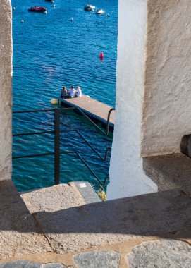 Three  tourists on the pier in the port of Cadaques, Spain
