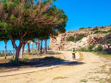 Bir adam Malaga sahilinde bir tünelin yanında bisiklet sürüyor..