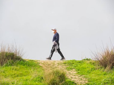 Emekli adam çalılıklarda yürüyor.