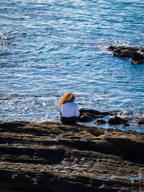 a woman is sitting on the beach 