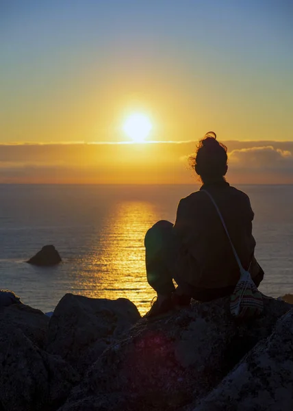 stock image girl with backpack and backpack looking at the horizon over the sea