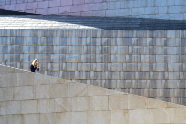 Saçları olan genç bir kadın Guggenheim Müzesi 'nin merdivenlerinden iniyor.