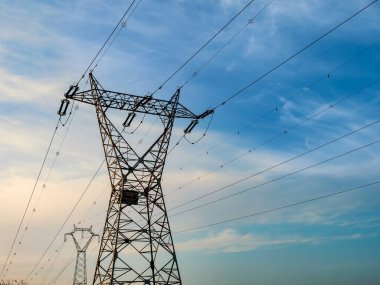 Mavi gökyüzünün arka planında yüksek voltajlı elektrik hatları