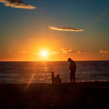 Gün batımında sahilde bir grup turistin siluetleri.. 