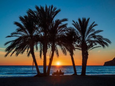 Çift bankta oturup La Herradura, Granada sahilinde gün batımını seyrediyor..