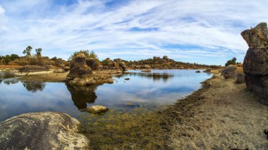 İspanya 'nın Caceres kentindeki Los Barruecos doğal parkında kayalar ve su.