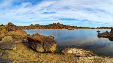 İspanya 'nın Caceres kentindeki Los Barruecos doğal parkında kayalar ve su.