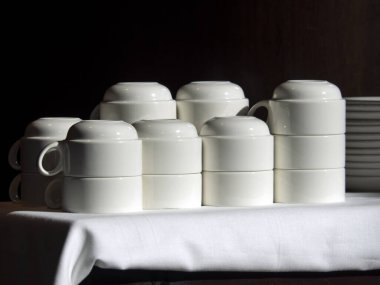 Siyah arka planda beyaz porselen tabaklar ve gölgeler.