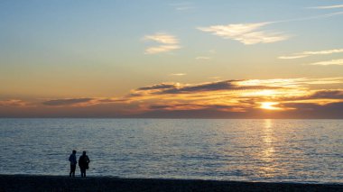 Gün batımında sahilde bir çift silueti.