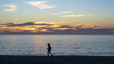 Gün batımında sahilde yürüyen bir kişinin silüeti, Cabo de Gata, Almeria, İspanya