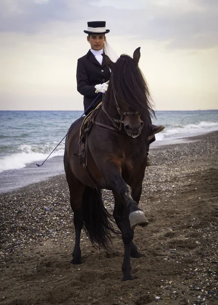 Sahilde ata binen şapkalı bir kadın.