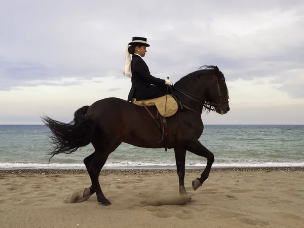 Sahilde ata binen bir kadın.