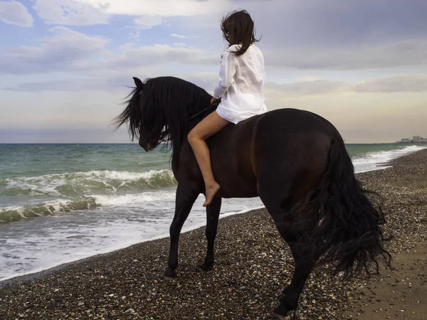 Sahilde ata binen bir kadın.