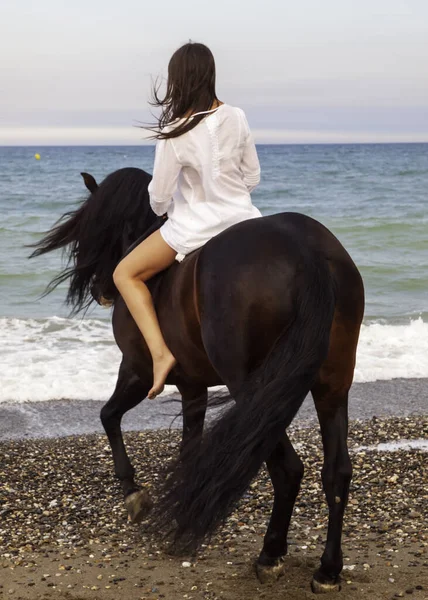 Sahilde ata binen bir kadın.