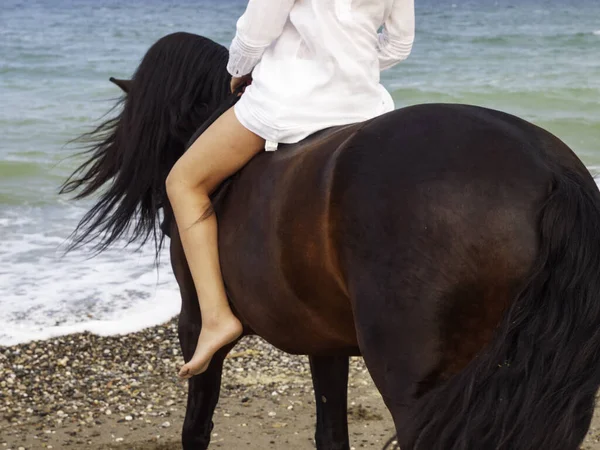 Sahilde ata binen bir kadın.