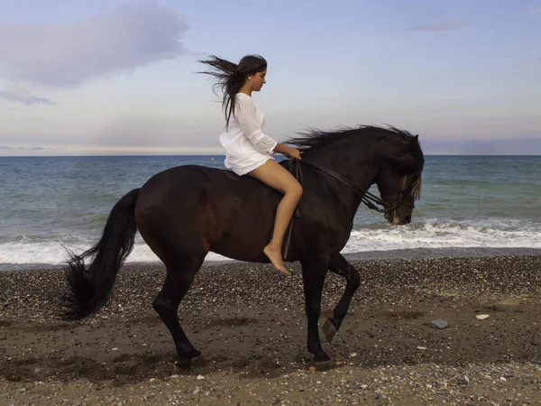 Sahilde ata binen bir kadın.