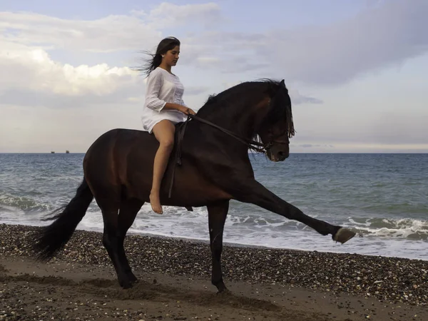 Sahilde ata binen bir kadın.