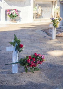 Mezarlıkta çiçekli bir haç.