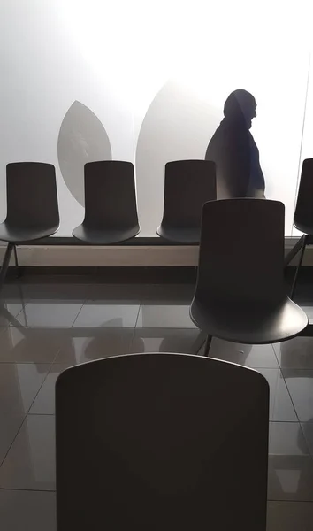 a person sitting in a waiting room with a lot of chairs