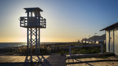 Cankurtaran kulesi olan bir sahile giden ahşap bir yol.