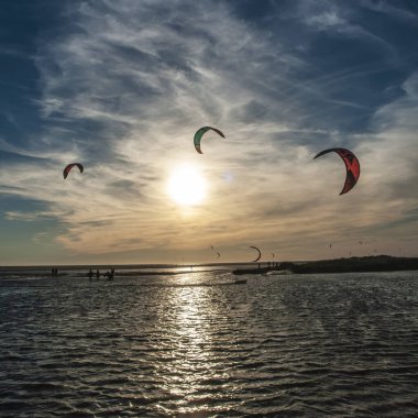 Uçurtması olan bir adam güzel bir gün batımının üzerinde uçuyor.